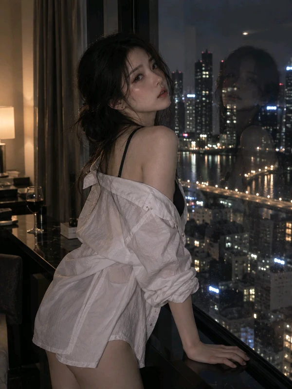 Woman in a pale open shirt beside a city apartment window
